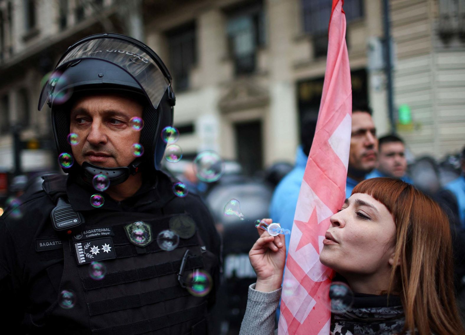 A demonstrator blows soap bubbles next to a member of the Buenos Aires police during a protest in Buenos Aires, Argentina, on Wednesday, August 6. The protest, in opposition of Argentine President Javier Milei, was held after he vetoed a pension increase and a bill strengthening protections for people with disabilities, which lawmakers had passed in July.