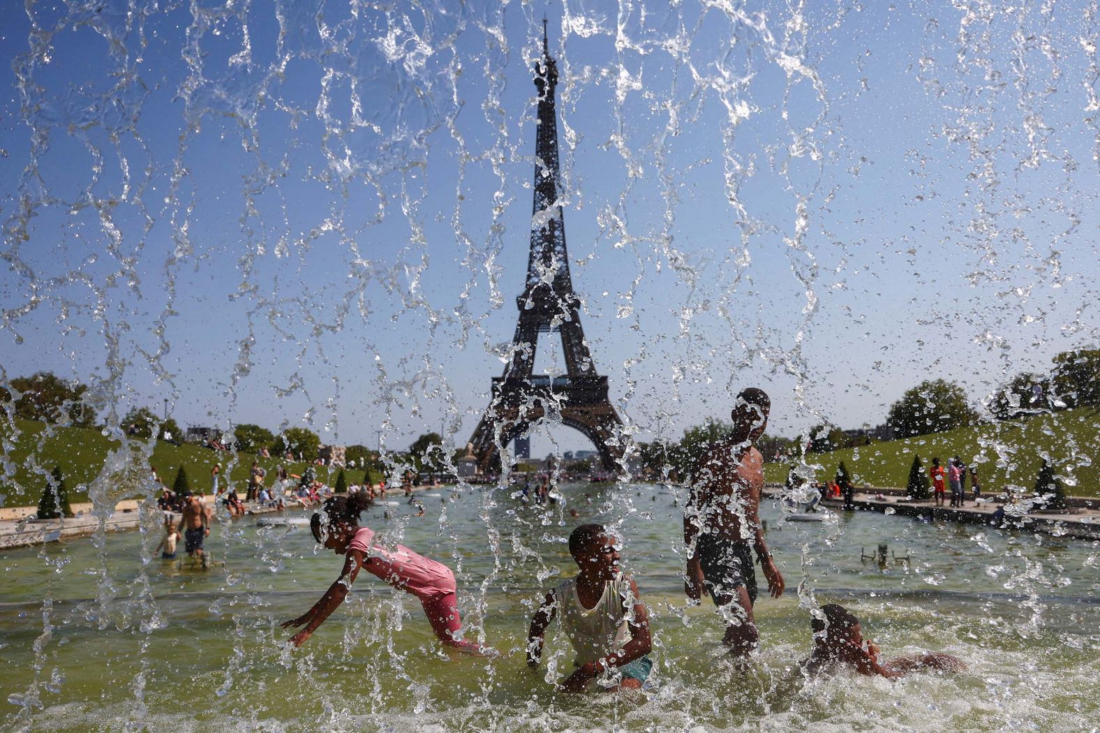 Children play in the water of the Fontaine du Trocadero in front of the Eiffel Tower on a summer day in Paris on Friday, August 15.