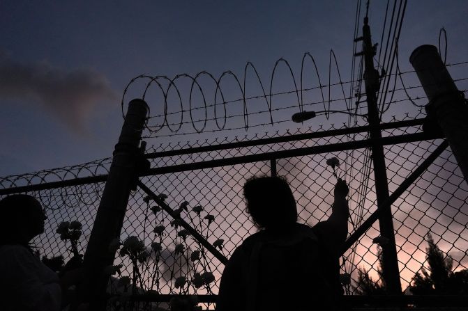People place flowers on a fence outside the Krome Detention Center in Miami on Saturday, May 24. It is the oldest immigration detention facility in the United States, according to the Associated Press.