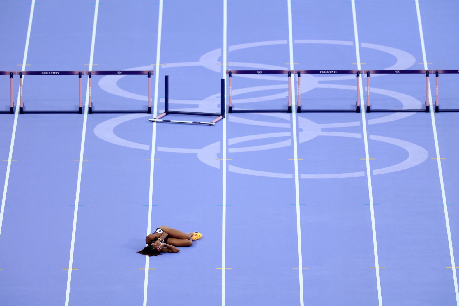 British athlete Lina Nielsen lies on the track after falling during a 400-meter hurdles race at the Olympics on Tuesday, August 6.