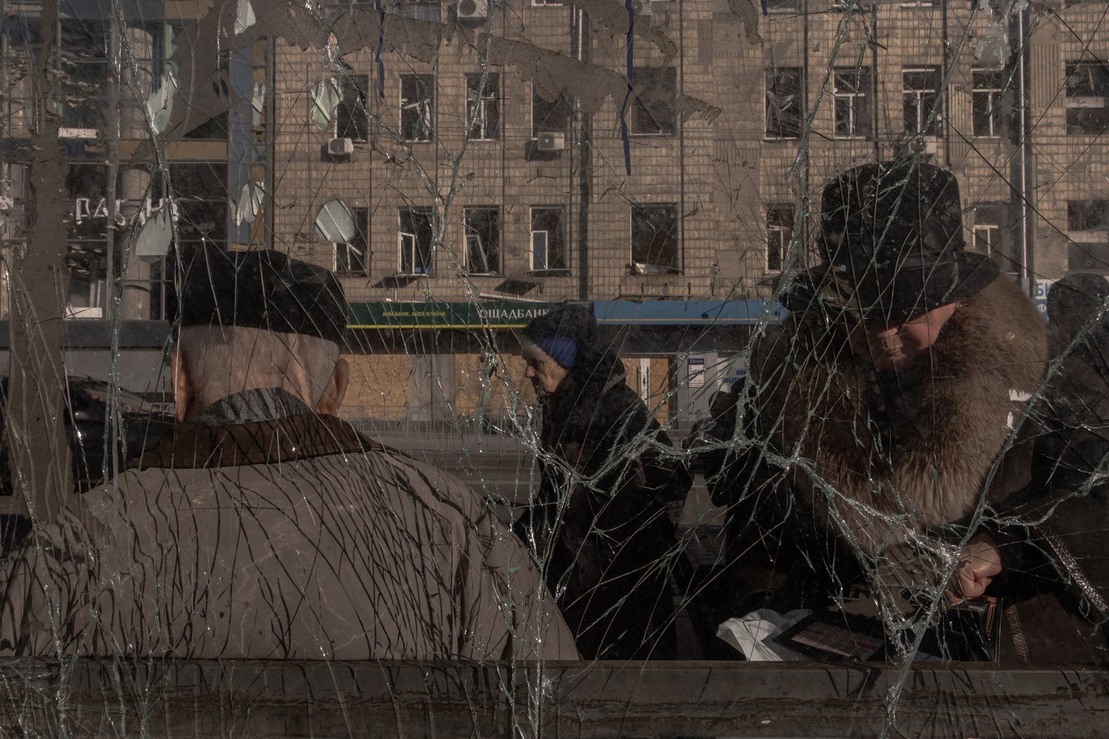 People wait at a damaged bus stop in Kyiv, Ukraine, on Sunday, January 19. A day earlier in Kyiv, three people were killed and three others were injured in a <a href="index.php?page=&url=https%3A%2F%2Fwww.cnn.com%2F2025%2F01%2F18%2Feurope%2Frussia-ukraine-strike-kyiv-atacms-intl%2Findex.html">Russian missile strike</a>, officials said.