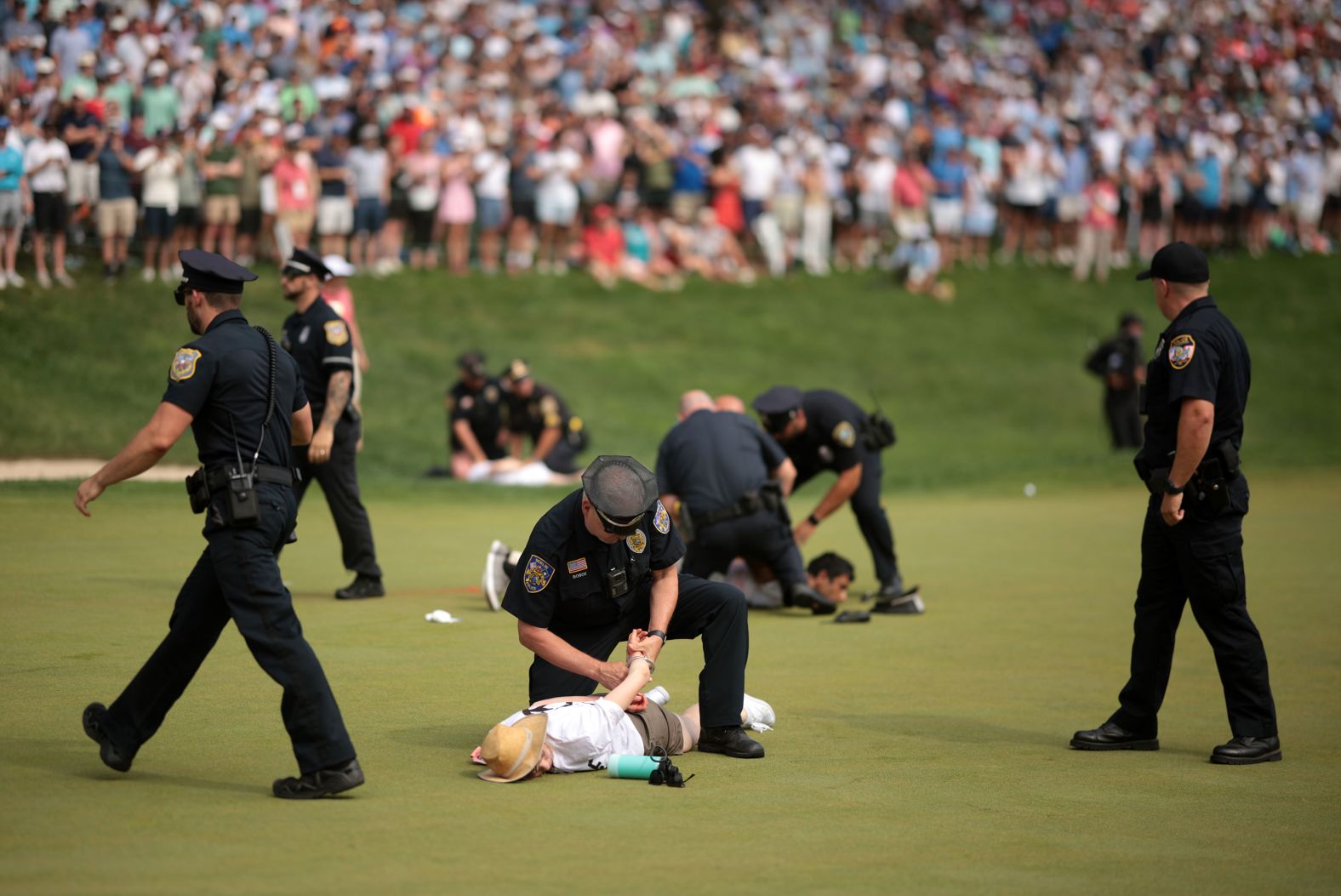 Climate protesters are detained by police on the 18th green after <a href="index.php?page=&url=https%3A%2F%2Fwww.cnn.com%2F2024%2F06%2F23%2Fsport%2Fprotesters-disrupt-travelers-championship%2Findex.html">they interrupted the final round of the PGA Tour’s Travelers Championship</a> in Cromwell, Connecticut, on Sunday, June 23. The protesters left a powdery substance on the putting surface and delayed play for several minutes.