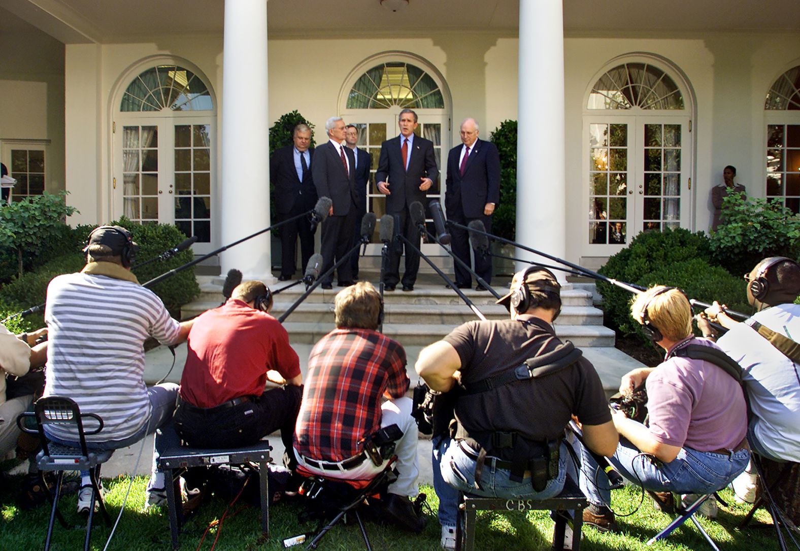 As broadcast soundmen reach in with microphones, President Bush, joined by Vice President Dick Cheney,right, and his economic advisers, outlines measures to boost the economy in the wake of the September 11 terrorist attacks as he speaks to reporters in the Rose Garden at the White House in Washington, Friday, October 5, 2001.