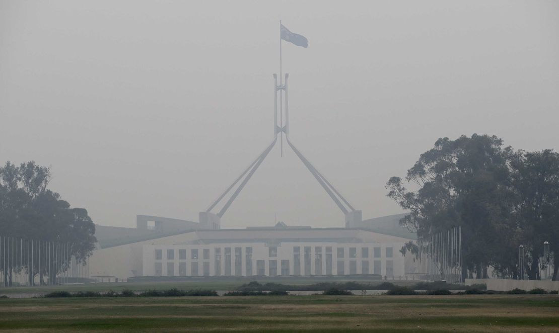 The Australian flag flies above Parliament House as smoke shrouds the Australian capital of Canberra, Australia, Wednesday, Jan. 1, 2020. 