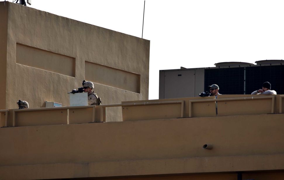 US Marines stand guard on the roof of the US Embassy while protesters demonstrate on Wednesday.