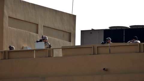 US soldiers stand guard on the roof of the US Embassy in Baghdad while pro-Iranian militiamen and their supporters protest outside the building.