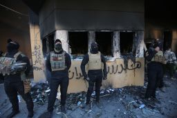 Iraqi security forces gather at the entrance of the US embassy in the Iraqi capital Baghdad on January 1, 2020, as smoke billows following a demonstration by supporters of the largely Iranian-trained Hashed al-Shaabi paramilitary force. - Thousands of Iraqi supporters of the largely Iranian-trained Hashed al-Shaabi paramilitary force had gathered at the embassy, outraged by US strikes that killed 25 Hashed fighters over the weekend. They marched unimpeded through the checkpoints of the usually high-security Green Zone to the embassy gates, where they broke through a reception area, chanting "Death to America" and scribbling pro-Iran graffiti on the walls. (Photo by AHMAD AL-RUBAYE / AFP) (Photo by AHMAD AL-RUBAYE/AFP via Getty Images)