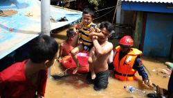 Rescuers evacuate a boy from his house in flooded neighborhood in Jakarta, Indonesia, Thursday, Jan. 2, 2020. Severe flooding in the capital as residents celebrated the new year has killed scores of people and displaced tens of thousands, the country's disaster management agency said.(AP Photo/Dita Alangkara)