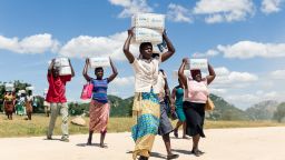 TOPSHOT - Women carry boxes load of porridge for their children, on March 13, 2019, in the Mutoko rural area of Zimbabwe. - Eastern Zimbabwe receives help to fight drought induced hunger, as a total of 32.000 villagers affected by drought in the Mutoko area. They received USD cash donations and children porridge donated by the World Food Programme (WFP) in partnership with USAID. (Photo by Jekesai NJIKIZANA / AFP)        (Photo credit should read JEKESAI NJIKIZANA/AFP via Getty Images)
