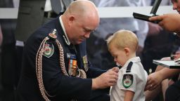 RFS Commissioner Shane Fitzsimmons puts the service medal of Geoffrey Keaton onto his son