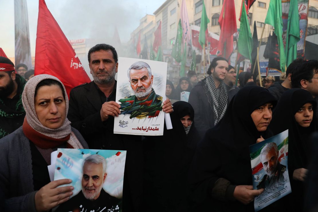 Mourners carry images of Soleimani, as they walk in the funeral procession in the Iranian capital.