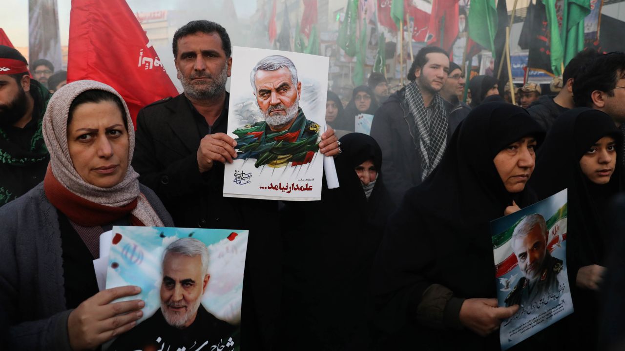 Mourners carry images of Soleimani, as they walk in the funeral procession in the Iranian capital.