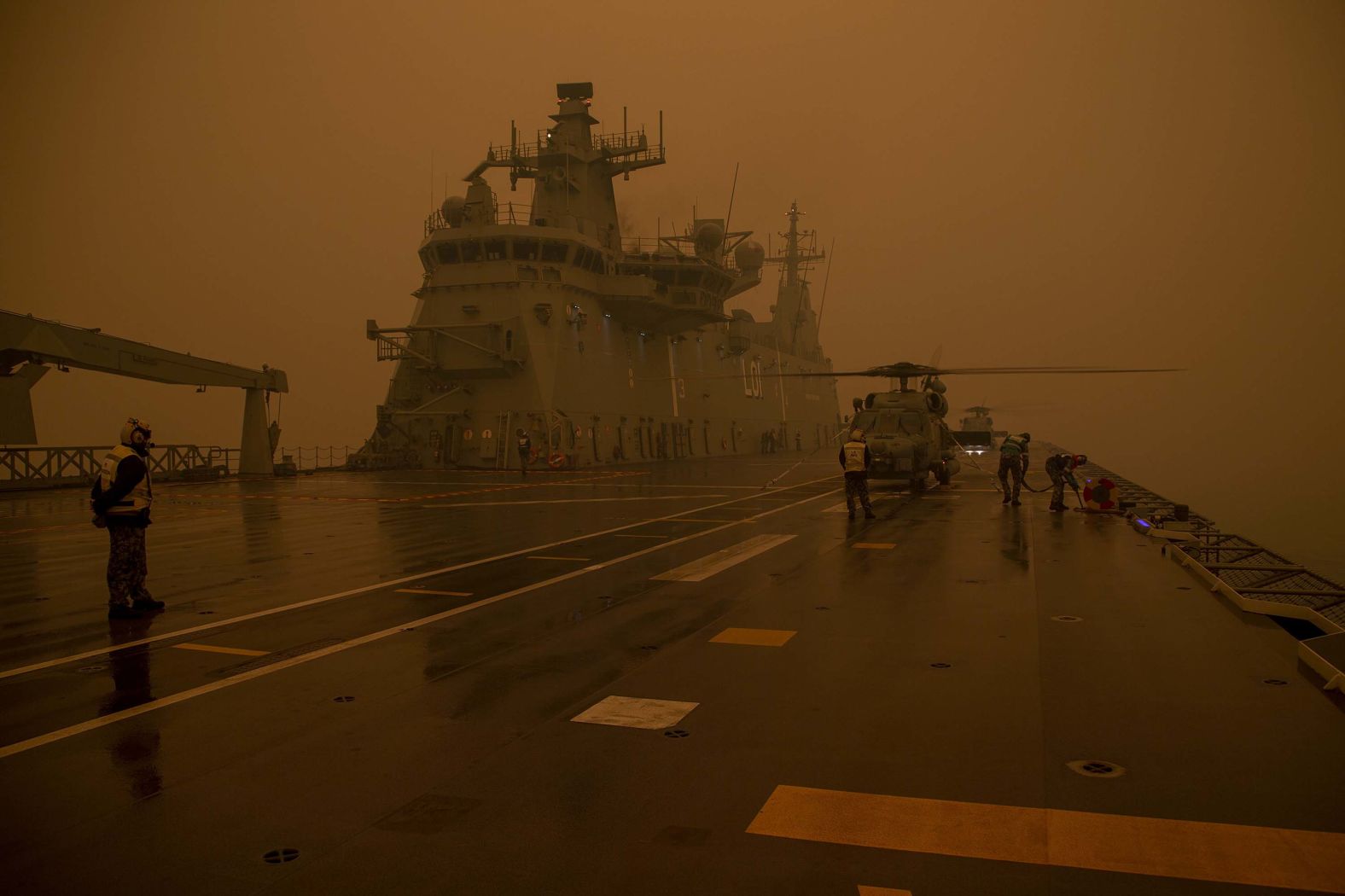 A Royal Australian Navy MH-60R Seahawk "Romeo" helicopter refuels onboard HMAS Adelaide during Operation Bushfire Assist, on Sunday, January 5, in this image provided by the Australian Department of Defence. HMAS Adelaide and army reserve forces have been assisting with bushfire evacuations on the southern coast of New South Wales.