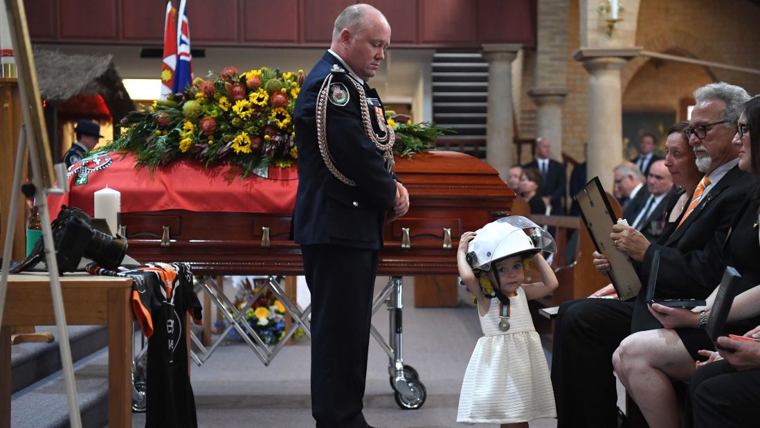 Charlotte O'Dwyer, the young daughter of Rural Fire Service volunteer Andrew O'Dwyer, wears her father's helmet during his funeral after being presented with a service medal in his honor by RFS Commissioner Shane Fitzsimmons on Tuesday, January 7, in Sydney.