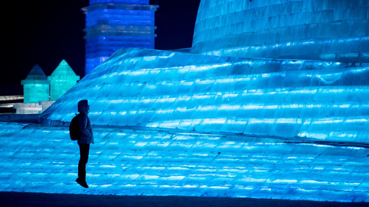 <strong>Strike a pose:</strong> A tourist poses in front of a lit-up ice sculpture.