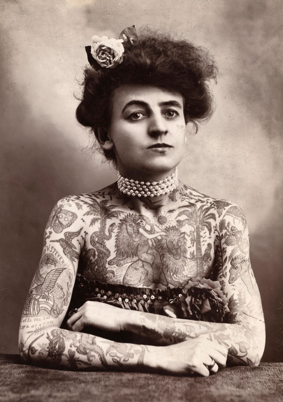 Portrait of a woman with tattooes or body paint covering her arms and chest.