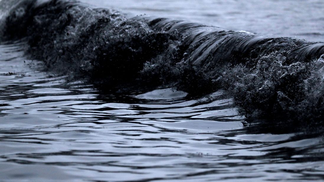 A small wave of black water full of burned debris breaks at a beach at Eden on January 9.