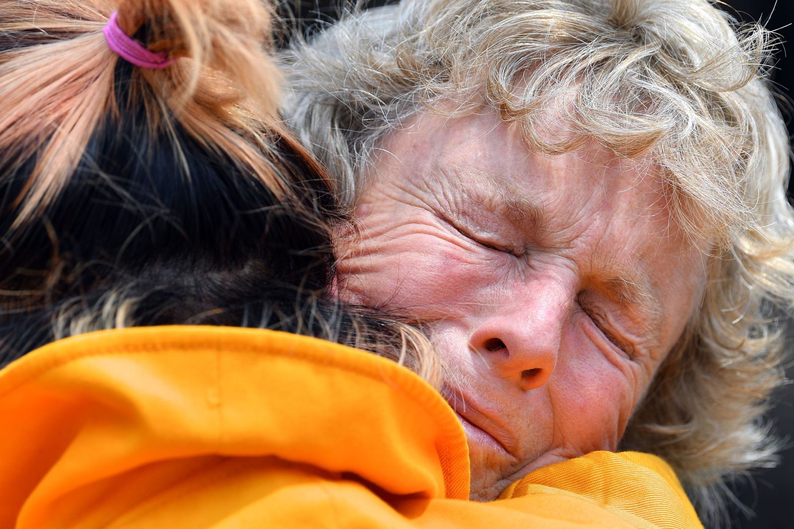 Stephenie Bailey is embraced on Wednesday, January 8, as she describes the impact the bushfires have had on her farm in Batlow.