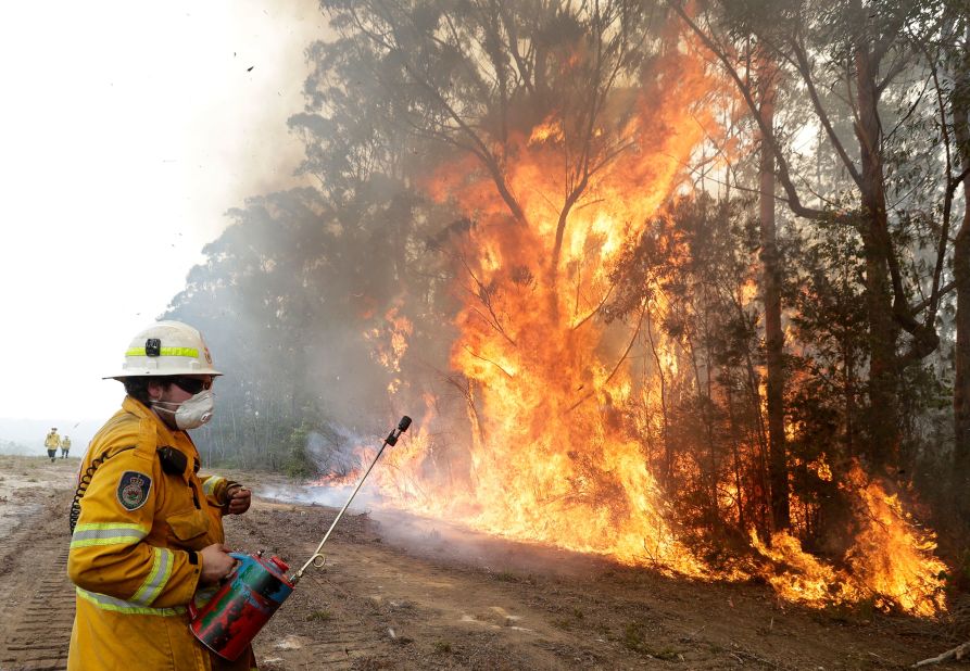 A firefighter backs away from flames after lighting a controlled burn near Tomerong on January 8.