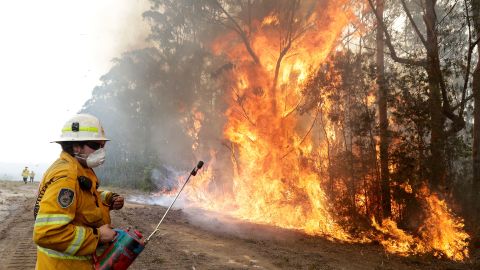 A firefighter backs away from flames near Tomerong, Australia.