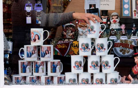 A shop worker in Windsor, England, adjusts memorabilia celebrating the engagement of Harry and Meghan. Their engagement <a href=