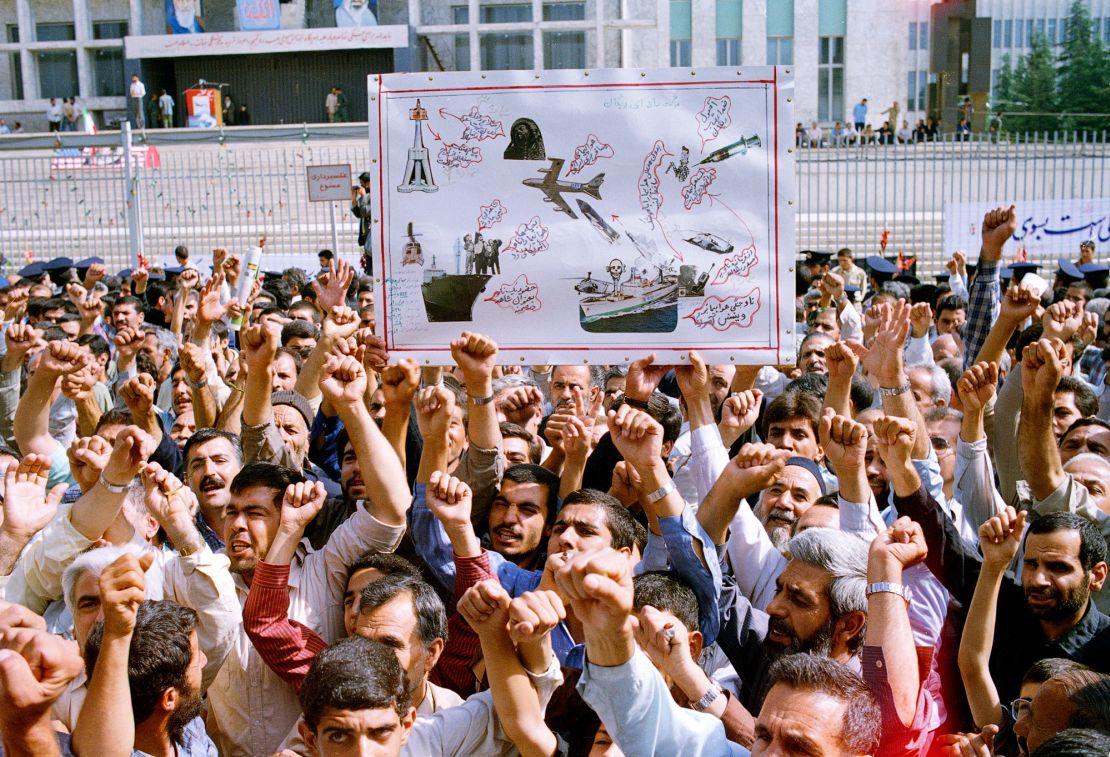 Thousands of Iranians chanting "Death to America," participate in a mass funeral for 76 people killed when the USS Vincennes shot down Iran Air Flight 655, in Tehran, Iran, July 7, 1988. They hold aloft a drawing depicting the incident. 