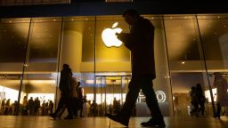 A man looks at his phone as he walks past a store of US tech giant Apple in a retail district in Beijing on Friday, Dec. 13, 2019.