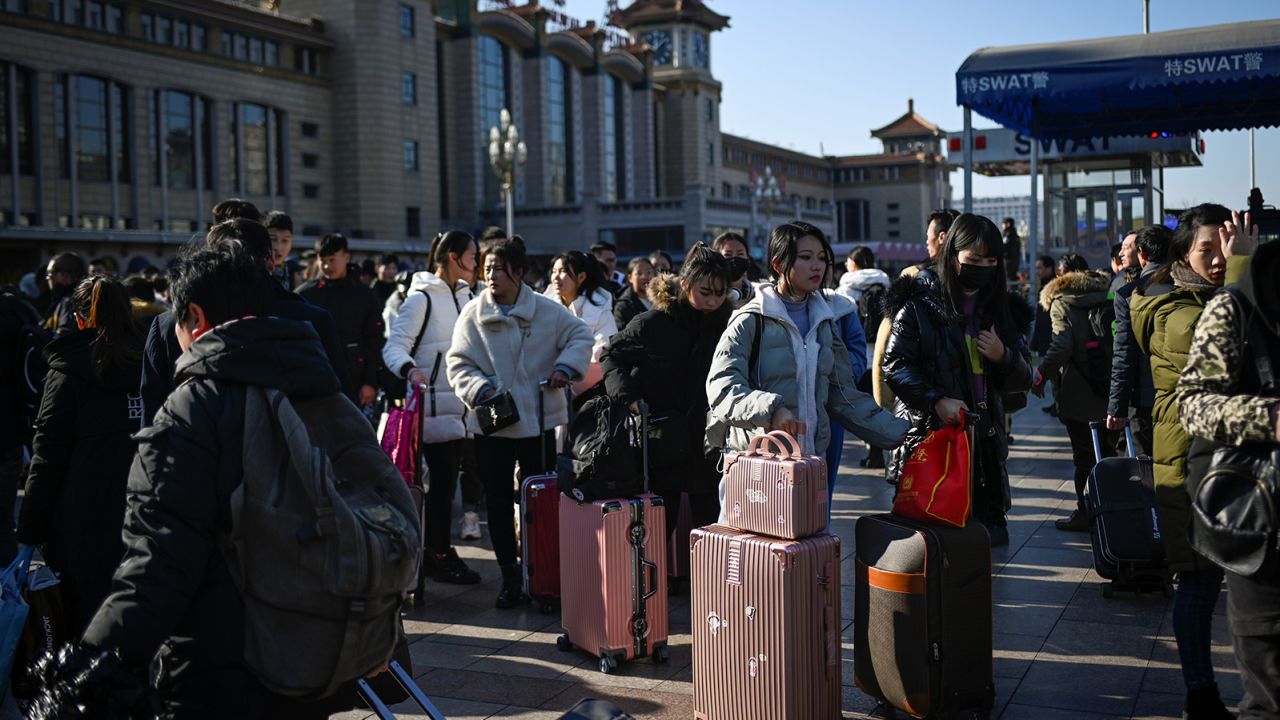 Travellers wait for their trains outside the entrance to Beijing railway station in the Chinese capital on January 10, 2020. 