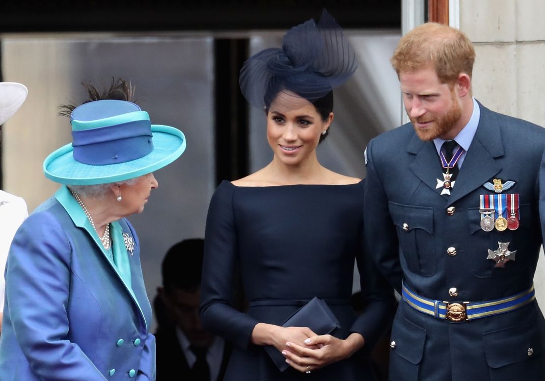 Queen Elizabeth II talks with the Duke and Duchess of Sussex during an RAF flypast of Buckingham Palace in 2018. 