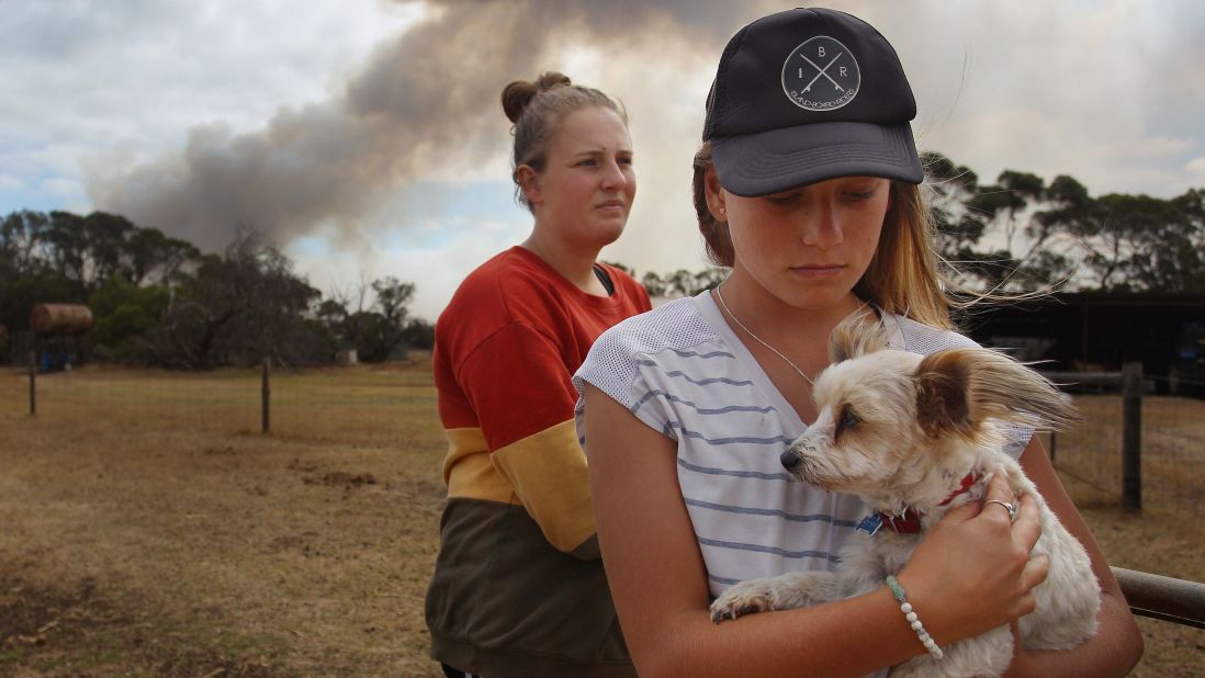 Bonnie Morris and sister Raemi Morris look on as their family and firefighters battle bushfires at the edge of their family farm in Karatta on Saturday, January 11.