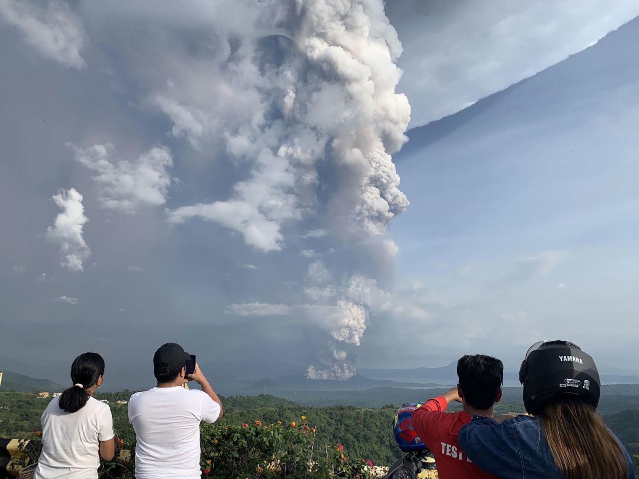 People take photos of the eruption on January 12.