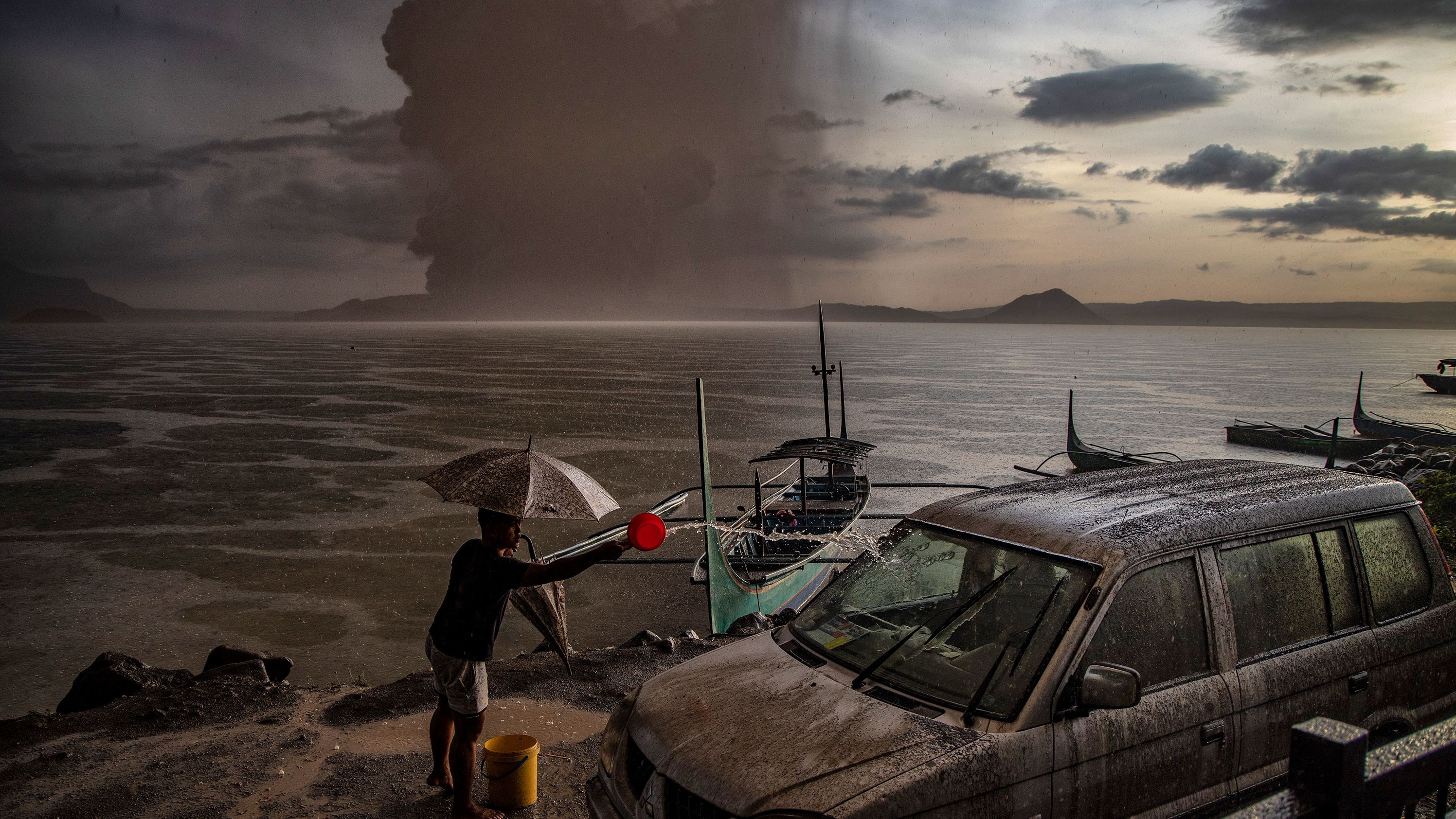 A Talisay resident splashes water on a vehicle covered in ash.