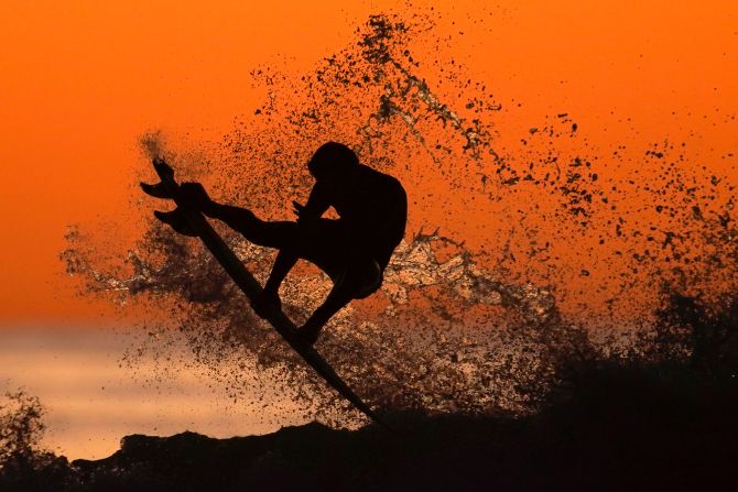 A surfer takes some air off a wave while surfing after sunset in Cardiff, California, on January 7, 2020.