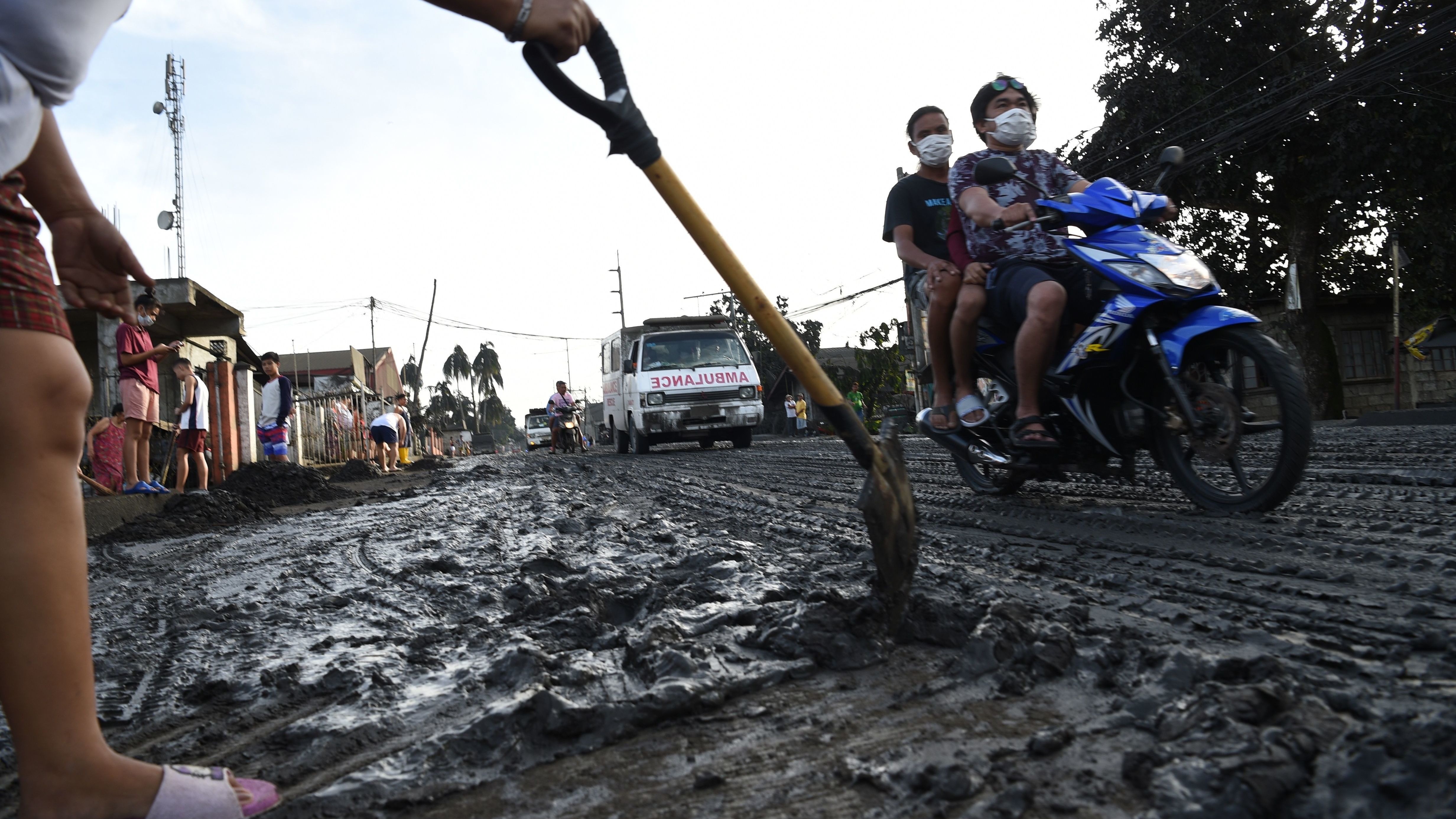 A Tanauan resident uses a shovel to clear mud and ash.