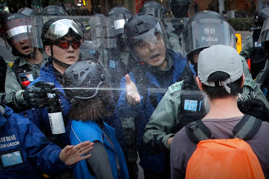 A riot policeman sprays pepper spray at a man as they disperse a crowd during a demonstration against "parallel traders" who buy goods in Hong Kong to resell in mainland China on Sunday, January 5.