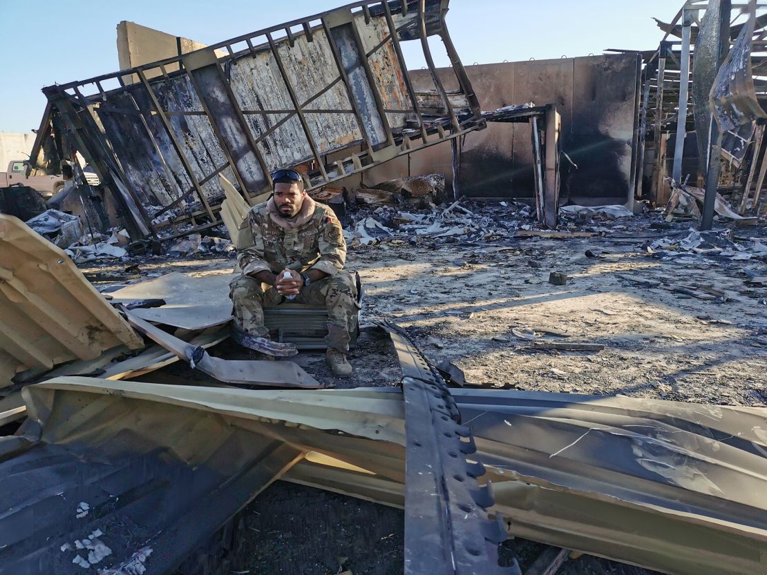 Sergeant Ferguson sits between charred metal at the site of the destroyed housing unit for drone pilots and operators.