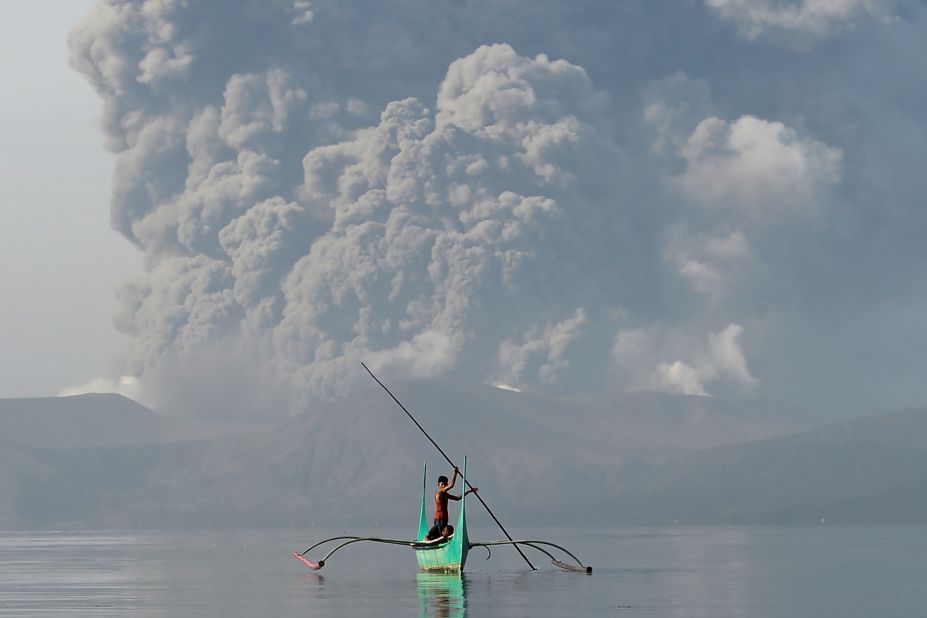 A youth rides an outrigger canoe while the volcano spews ash on January 13.
