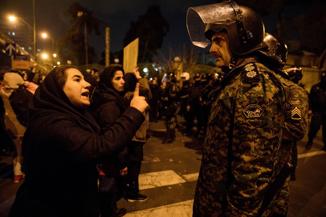 A woman attending a candlelight vigil for the victims of the Ukraine International Airlines crash, talks to a policeman following the gathering in front of the Amirkabir University in Tehran.