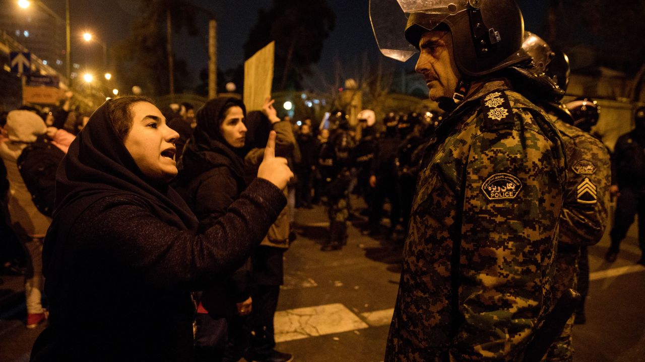 A woman attending a candlelight vigil for the victims of the Ukraine International Airlines crash, talks to a policeman following the gathering in front of the Amirkabir University in Tehran.