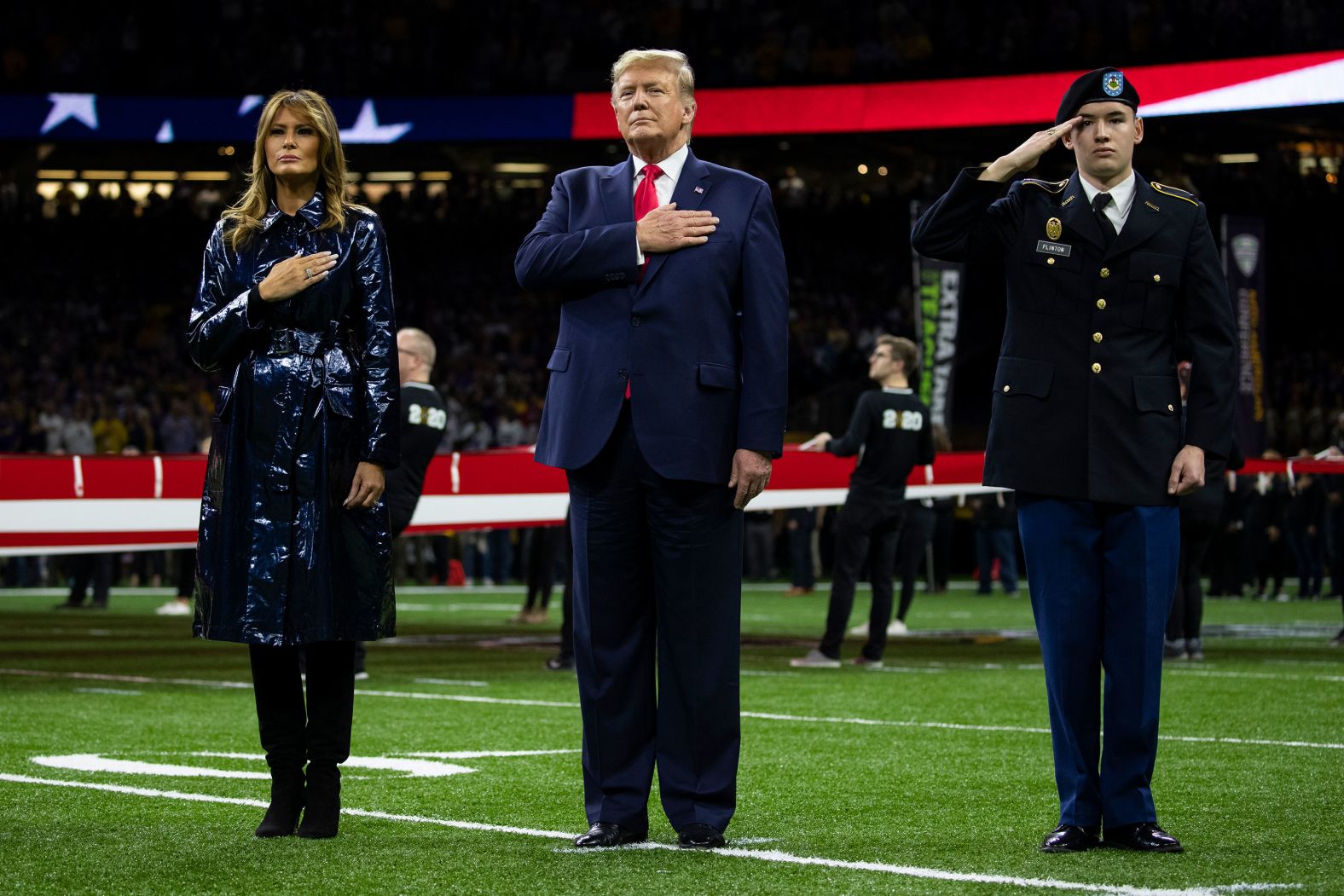 US President Donald Trump and first lady Melania Trump stand on the field for the National Anthem.