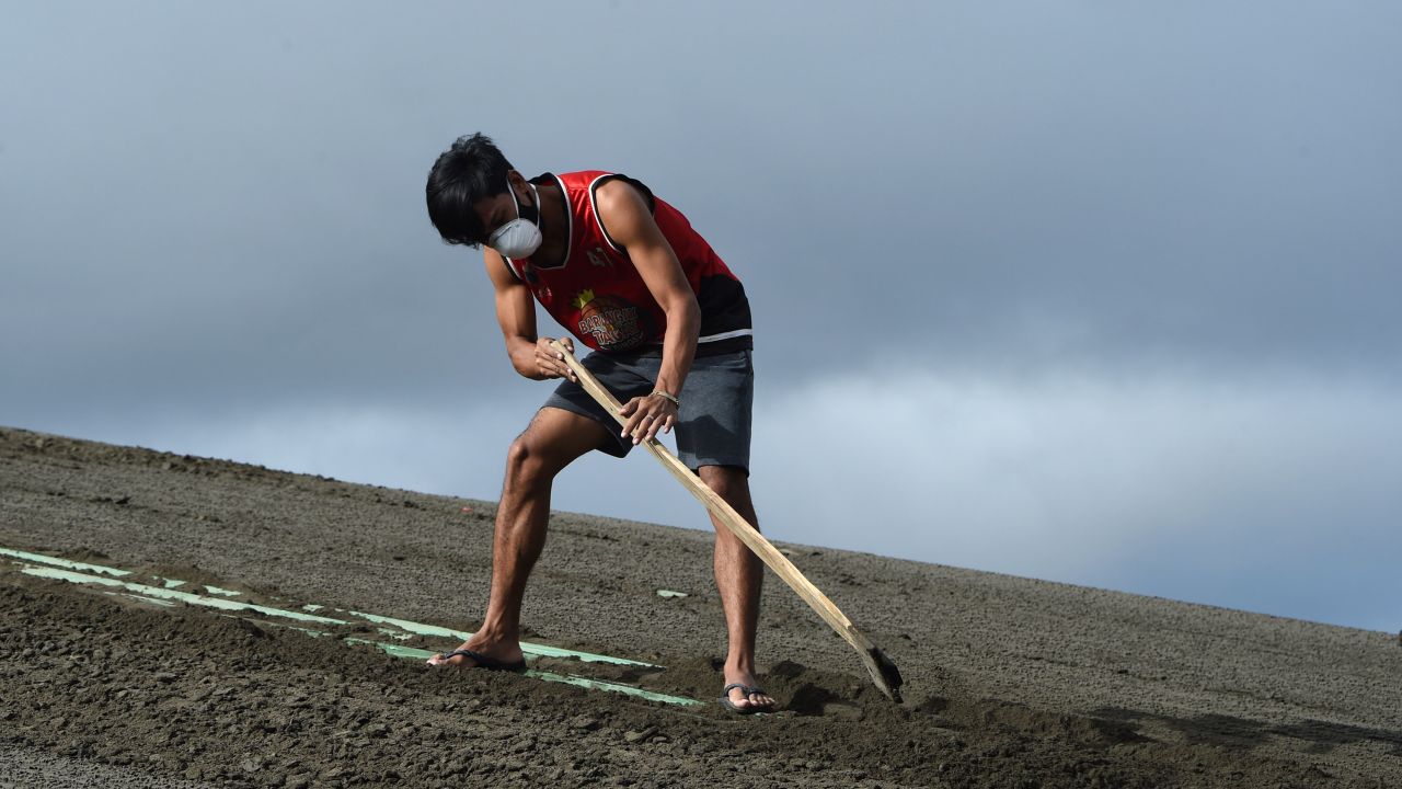 A resident cleans the roof of their house filled with ash spewed by Taal volcano in Tagaytay city.