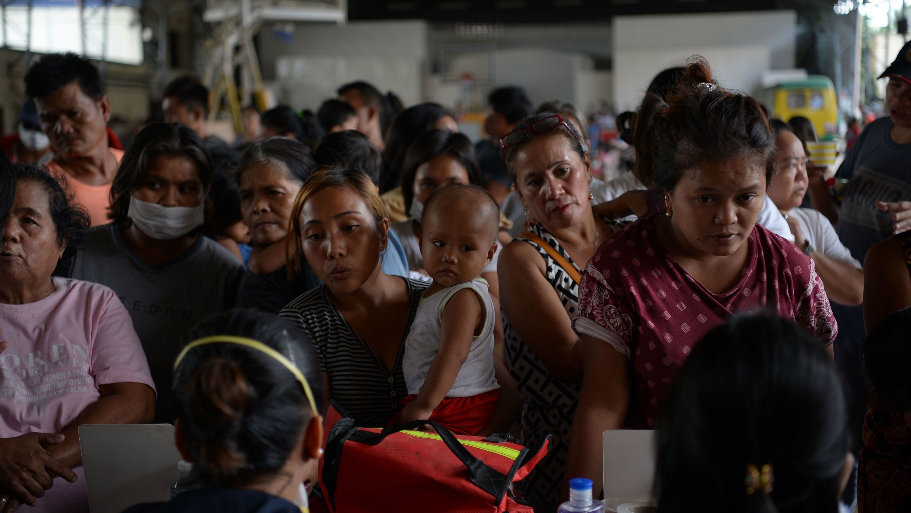 Evacuees line up to have their children checked by medical personnel at an evacuation center in Tanauan.
