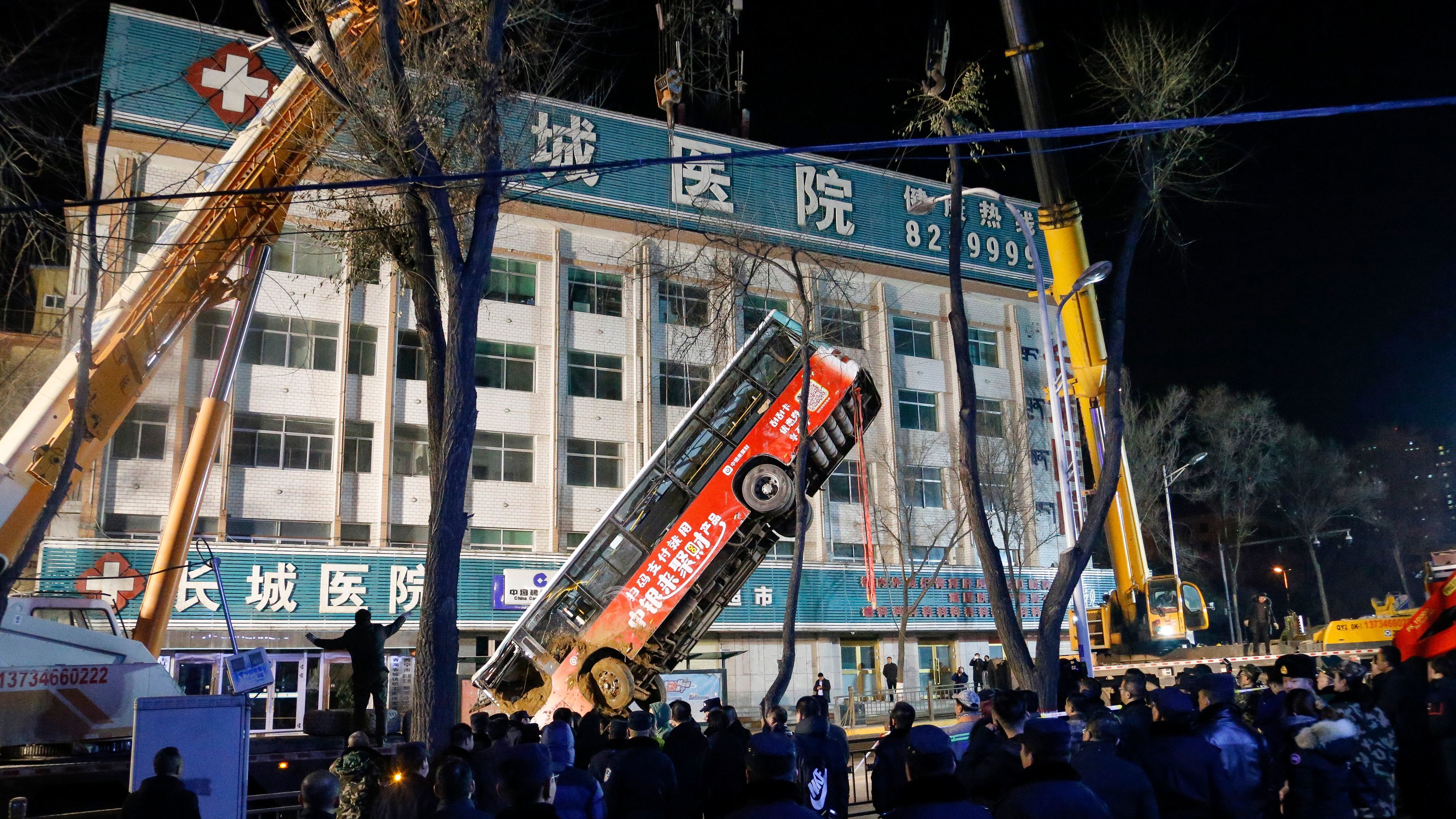 A bus swallowed by a huge sinkhole is lifted out after a road collapsed in Xining in China's northwestern Qinghai province.