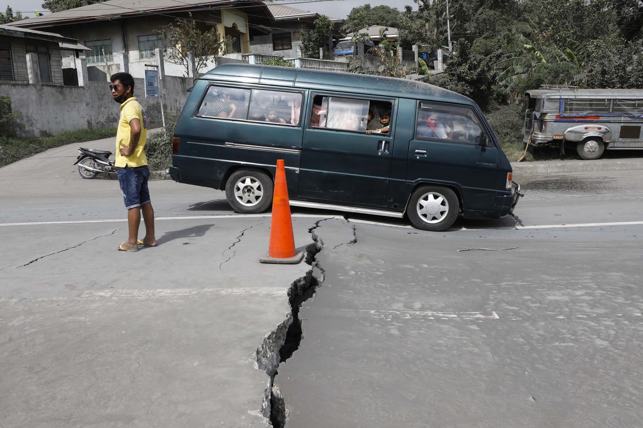 A family crosses a road that was damaged by volcanic tremors in Lemery.