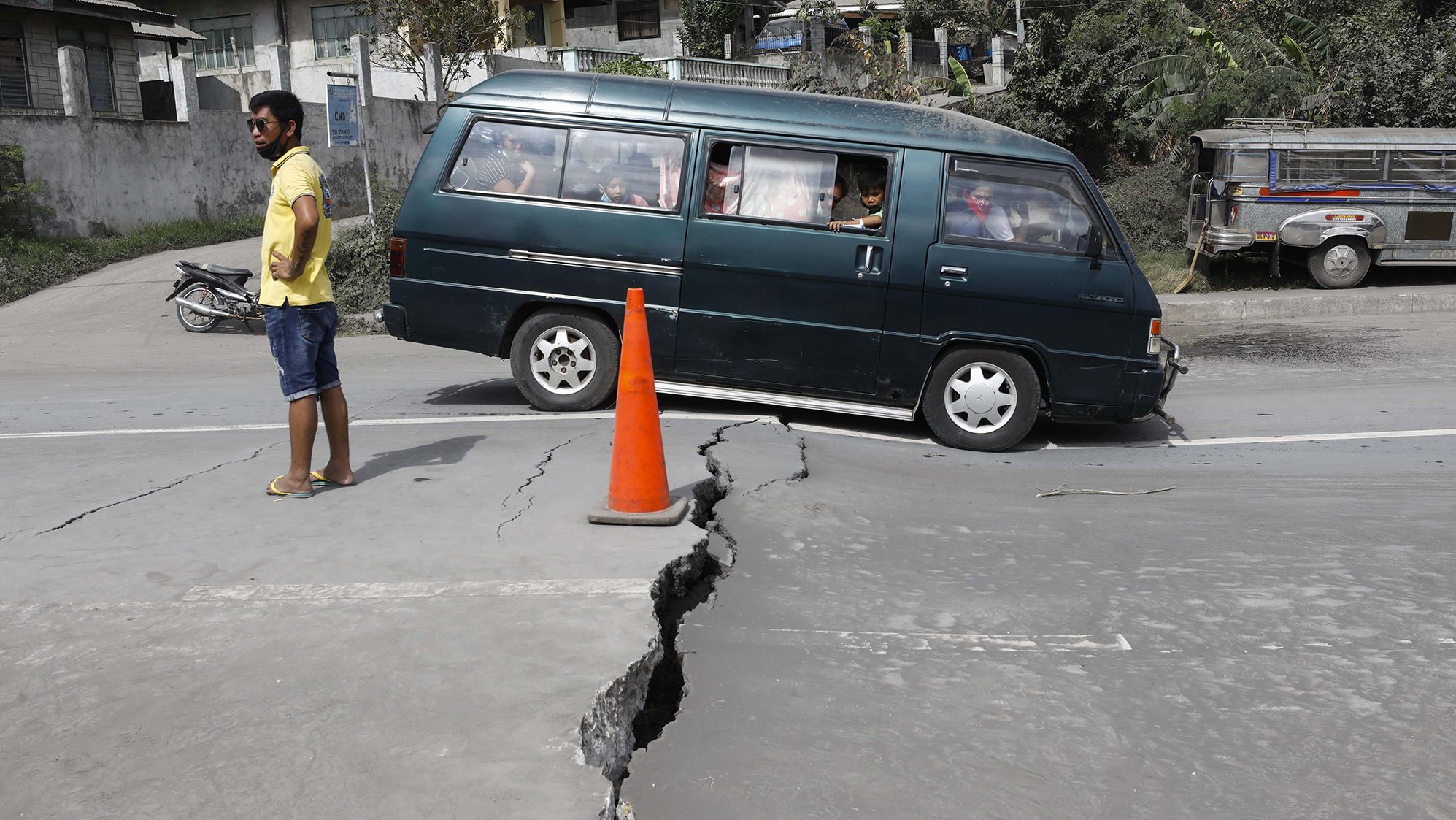 A family crosses a road that was damaged by volcanic tremors in Lemery.