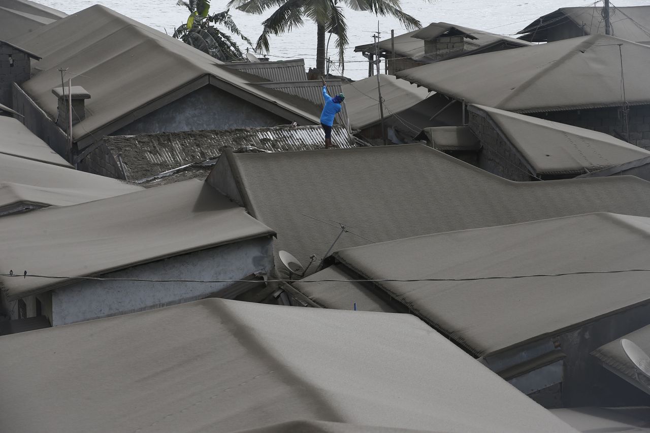 A resident cleans ash from his roof in Agoncillo on Tuesday, January 14.
