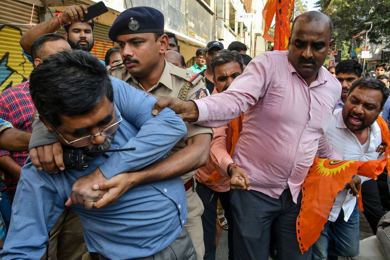 Police personnel try to protect a man attending a protest against graffiti on the shutters and walls of Church Street condemning Indian Prime Minister Narendra Modi and India's new citizenship law in Bangalore on Tuesday, January 14.
