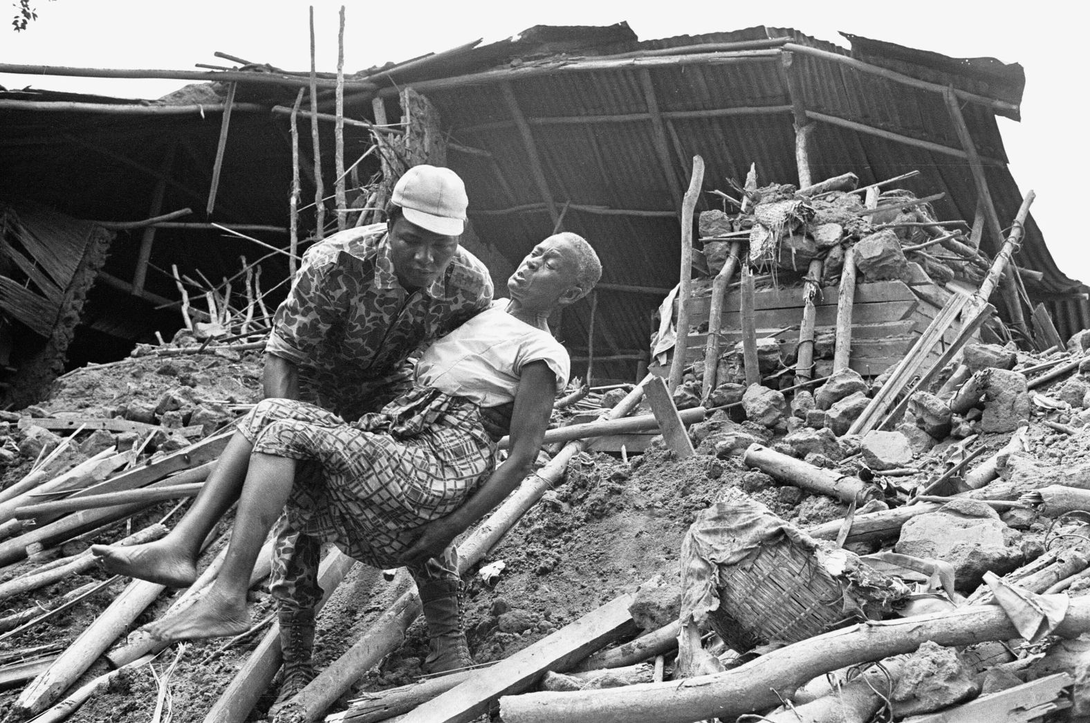 A Biafran soldier carries an elderly woman from the wreckage of her home following an artillery bombardment by the Nigerian army in June 1968.