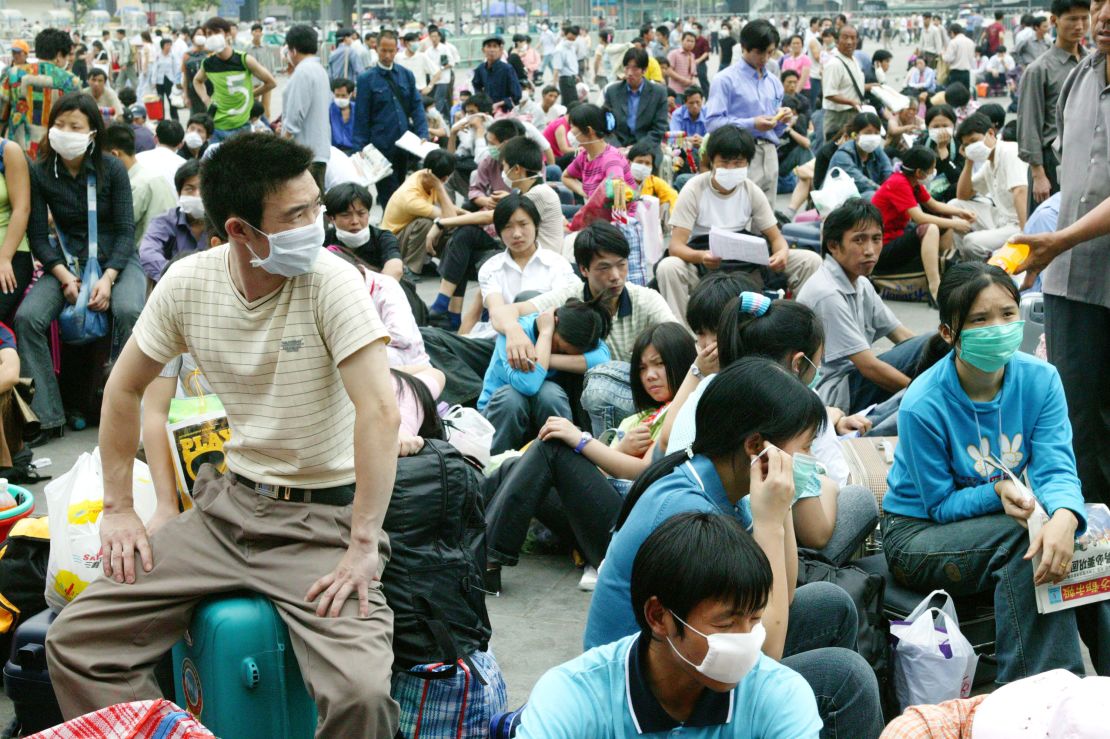 Migrant workers wait outside the Guangzhou train station before returning home because of the worry over SARS during the deadly epidemic in 2003. 