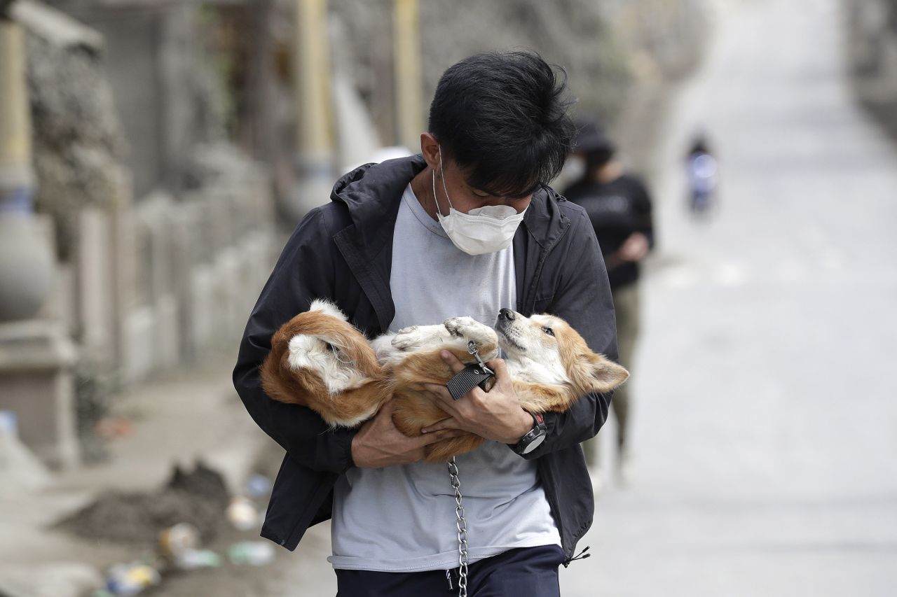 A volunteer carries a dog he rescued from deserted homes in Talisay.